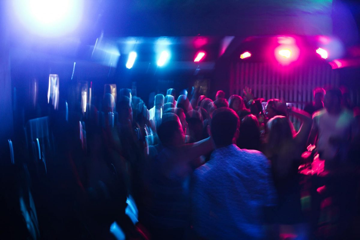 Vibrant nightclub scene with blurred dancing crowd and colorful lights.