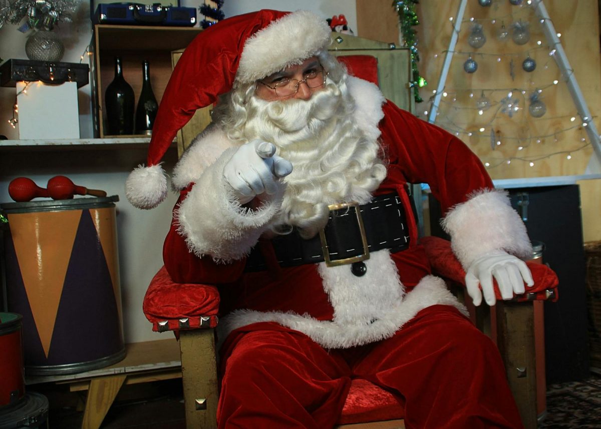 Santa Claus in a cozy room pointing cheerfully for a festive holiday vibe.