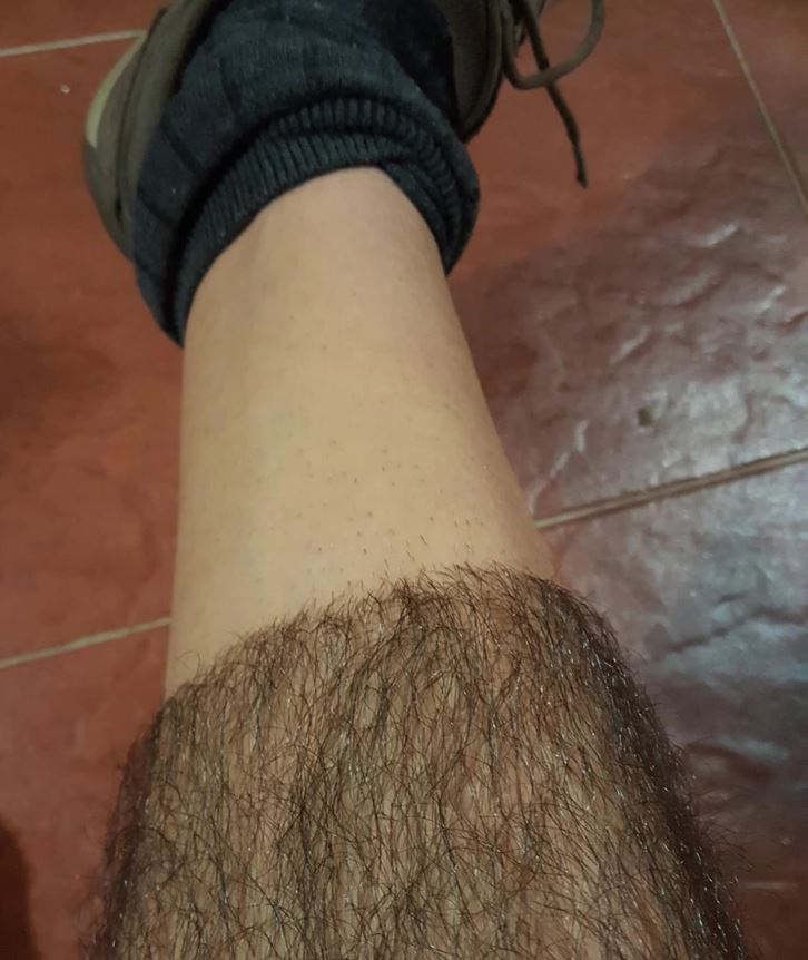 Dolná časť nohy osoby v ponožke a topánke na červenej dlážke.