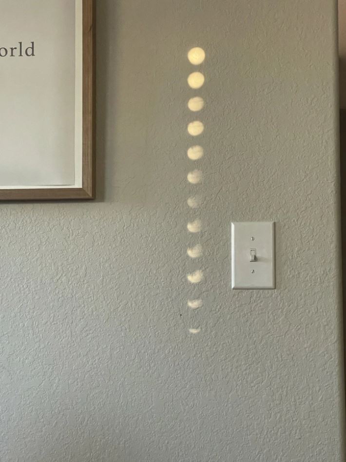 Slnko cez okno tvorí kruhy svetla na stene vedľa vypínača.