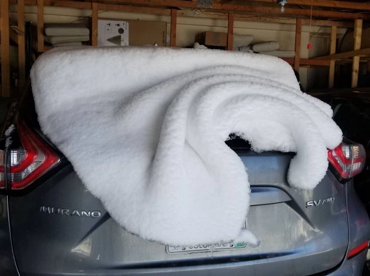 Auto s veľkou vrstvou snehu na zadnej časti, pripomínajúce prikrývku.