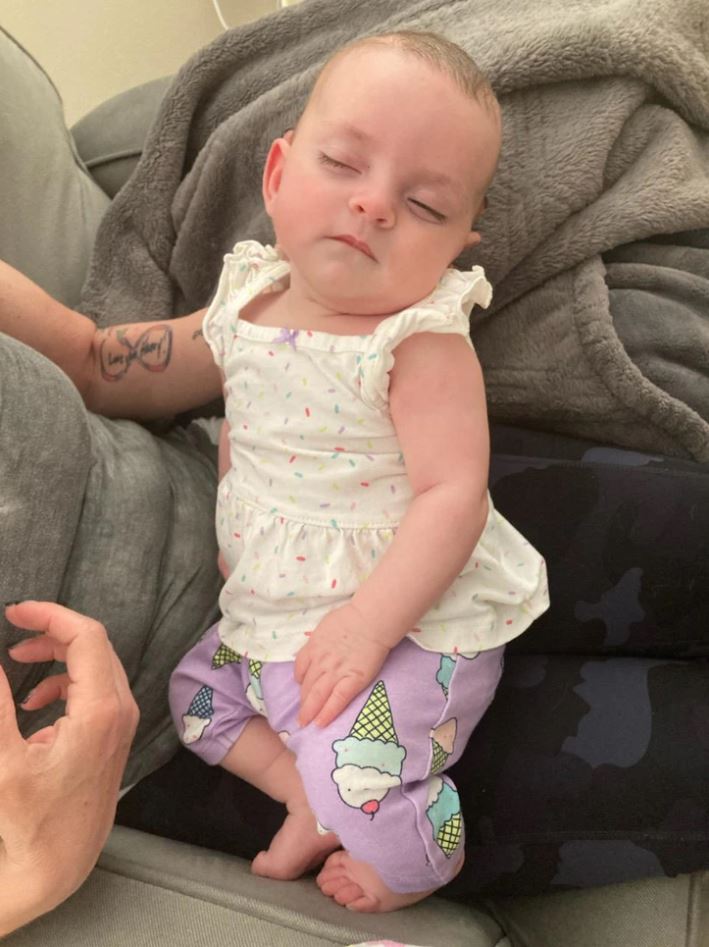 Dieťa v pohode oddychuje na gauči, oblečené v bielej blúzke a fialových nohaviciach so vzorom zmrzliny.