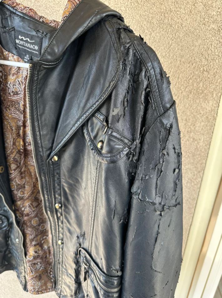 Kožená bunda s opraným vzhľadom a vzorovanou podšívkou na vešiaku.