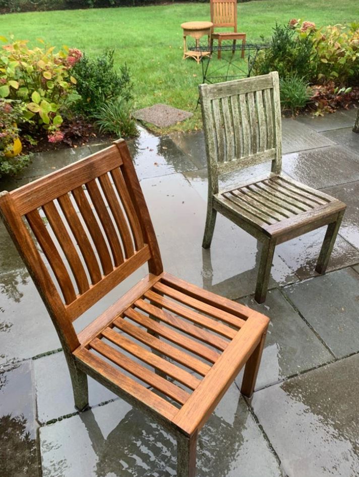 Drevené stoličky na mokrom dvore po daždi, zelená tráva a rastliny v pozadí.