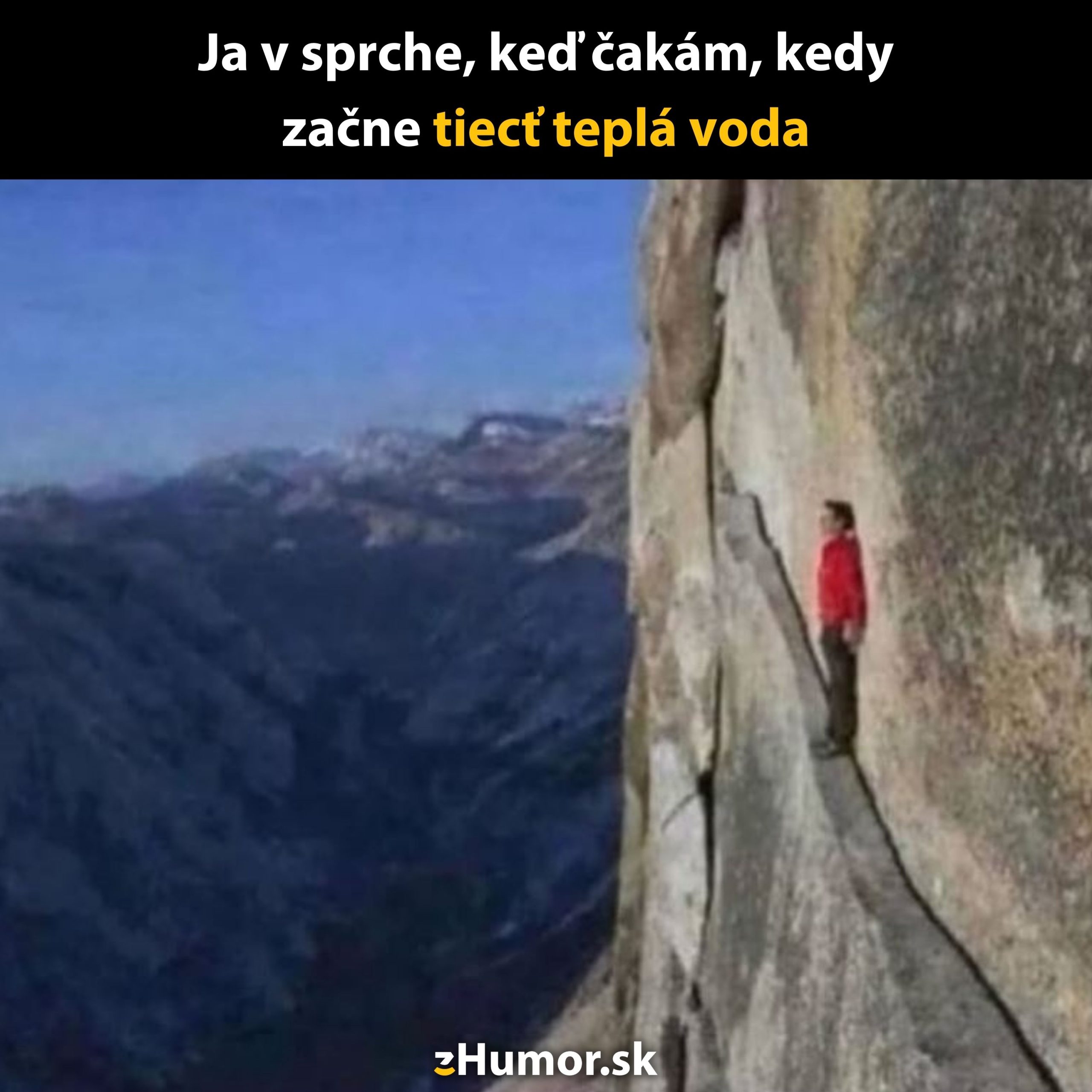 Osoba v červenej bunde stojí na úzkej rímske vysoko nad skalnatým údolím.