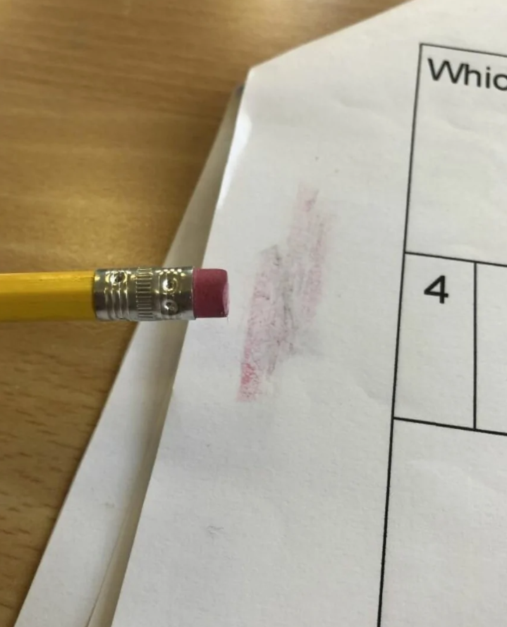 Ceruzka s gumou maže červenú ceruzku na bielom papieri.