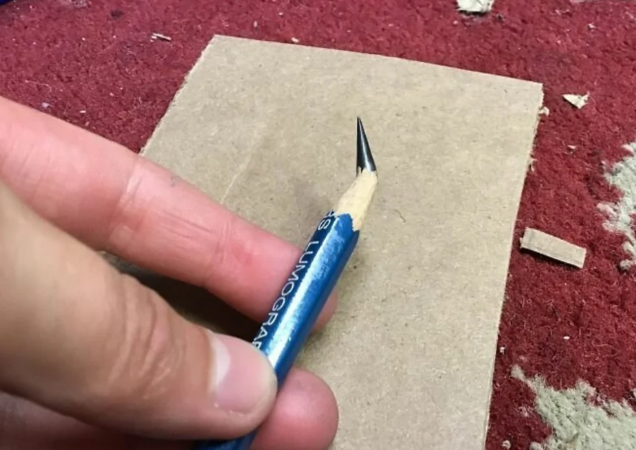 Ceruzka s neobvykle dlhou ostrou špičkou na kartóne, držiaca sa v ruke.