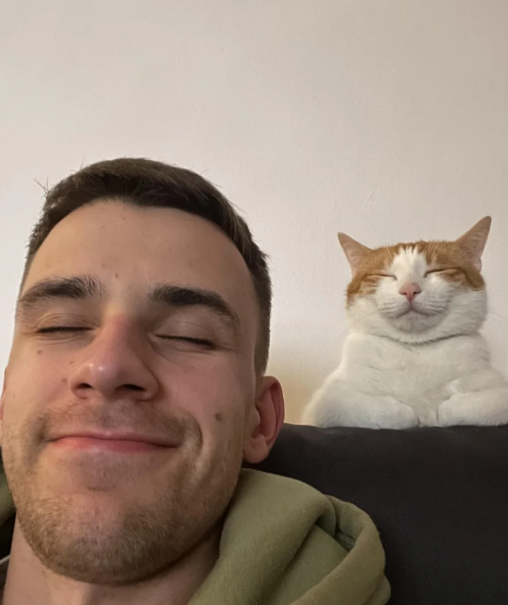 Osoba a mačka s blaženým úsmevom sediace vedľa seba, harmonická chvíľa pokoja a šťastia.