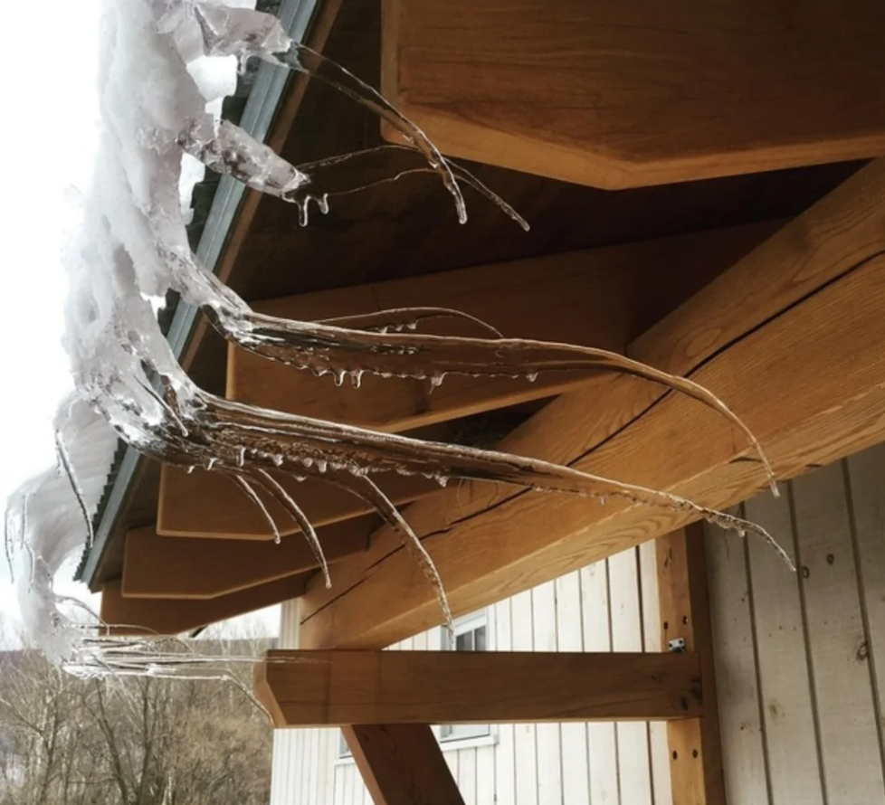 Ľadové cencúle tvorené na krove drevenej strechy po zimnej búrke.