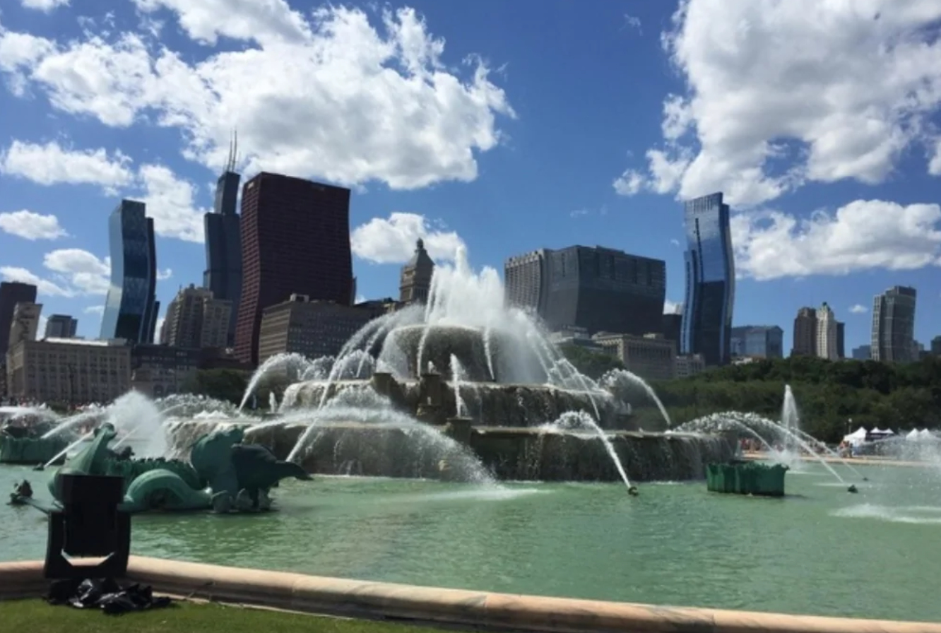 Fontána Cascades pred modernými mrakodrapmi pod modrou oblohou s bielymi oblakmi.