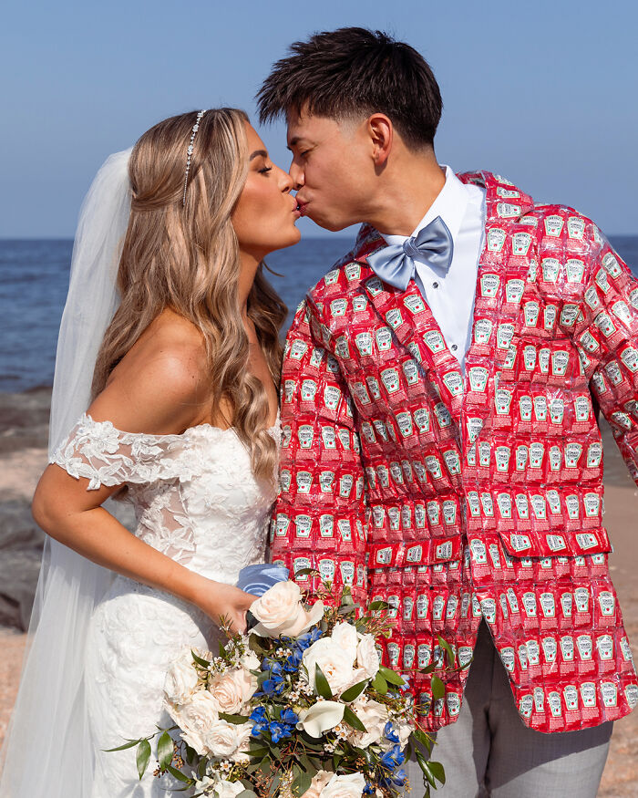 Nevesta a ženích sa bozkávajú na pláži, ženích má sako s dizajnom fľašiek od kečupu.