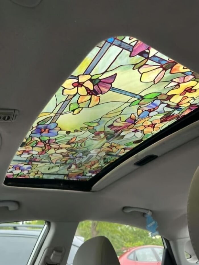 Auto s vitrážovým strešným oknom s farebnými kvetmi a listami, pohľad zvnútra.