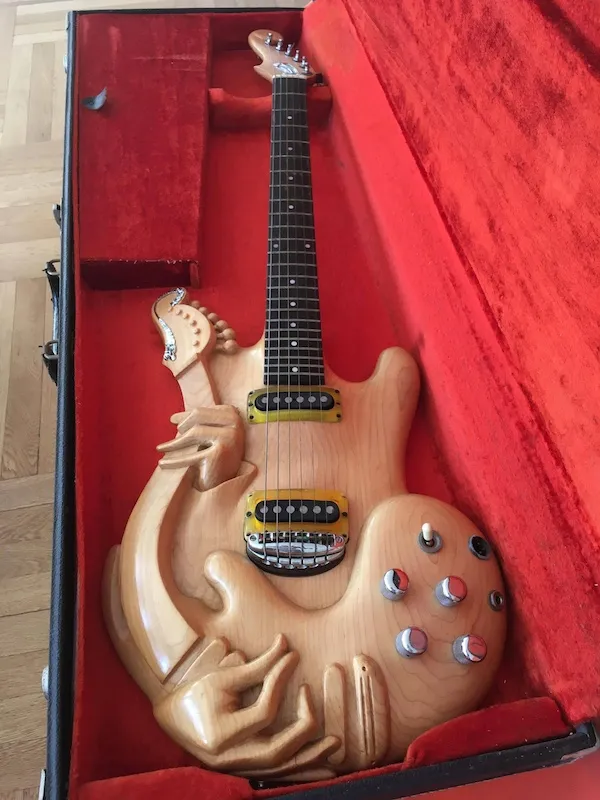 Elektrická gitara s unikátnym dizajnom draka v červenom puzdre.