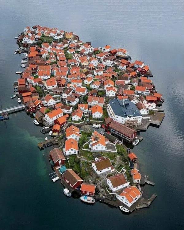 Malebný ostrov so stiesnenými domami a oranžovými strechami obklopený pokojným morom.