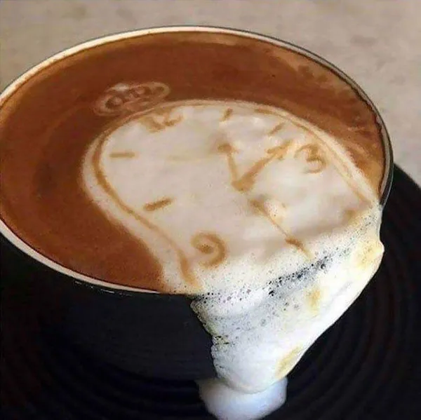 Káva s kreatívnym latte art, napodobňujúca známu tému roztápajúcej sa hodiny, odkaz na surrealistické umenie.