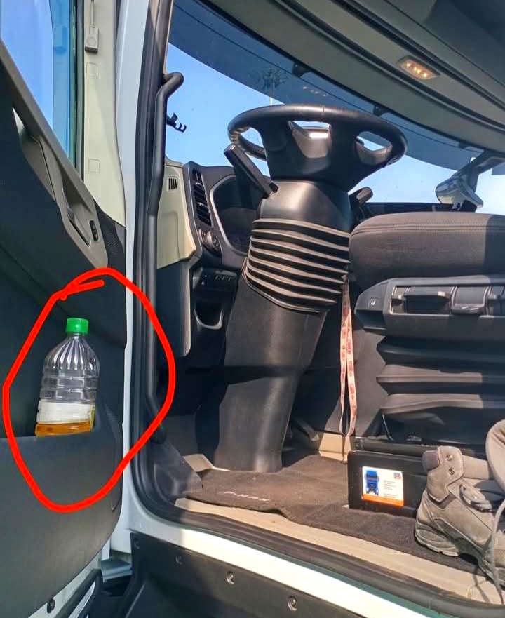 Vnútro kabíny nákladného auta s plastovou fľašou na nápoj v držiaku dverí, zvýraznené červeným kruhom.