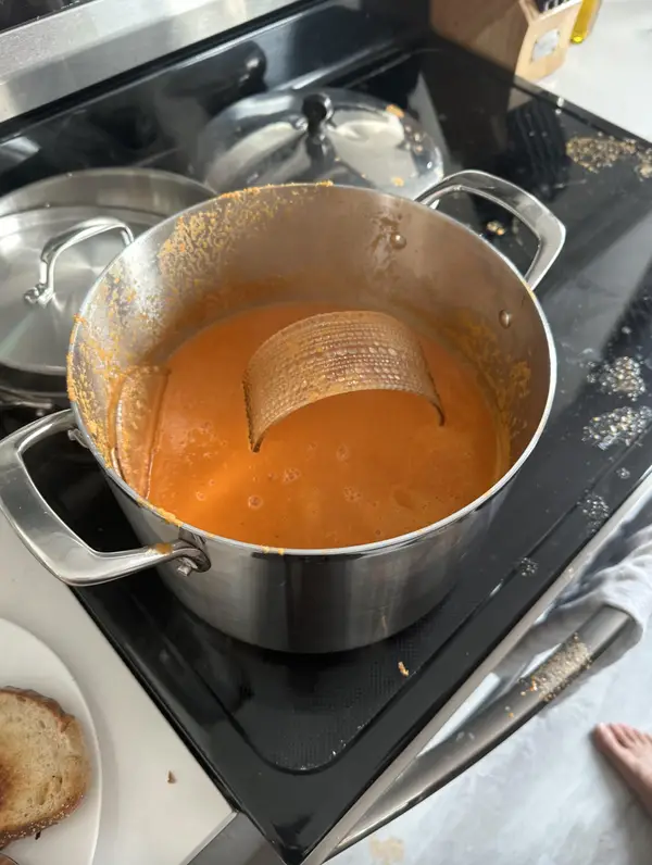 Hrniec s paradajkovou polievkou na sporáku s nečakaným predmetom vo vnútri, ktoré spôsobilo prekvapenie.