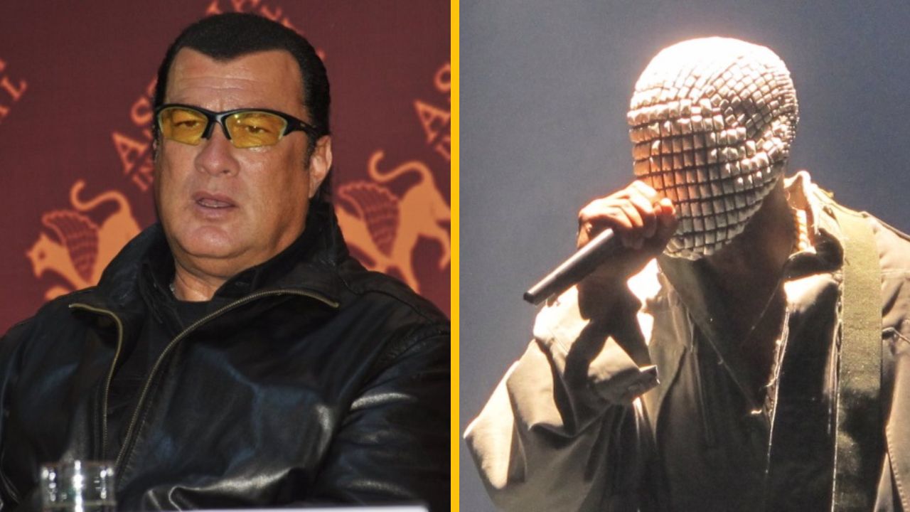 Osoba v koženej bunde na tlačovej konferencii vedľa maskovanej osoby s mikrofónom na pódiu.