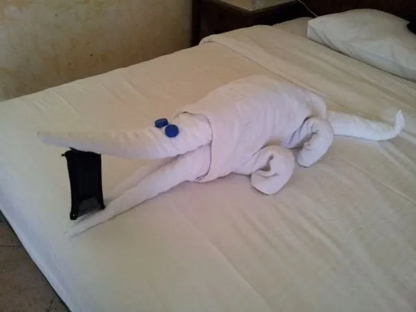 Zvieracia figúrka z uterákov položená na posteli v tvare krokodíla.