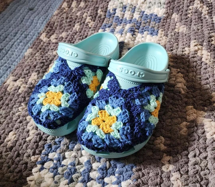 Pohodlné modré sandále s háčkovaným poťahom v rôznych farbách na pestrofarebnom koberci.