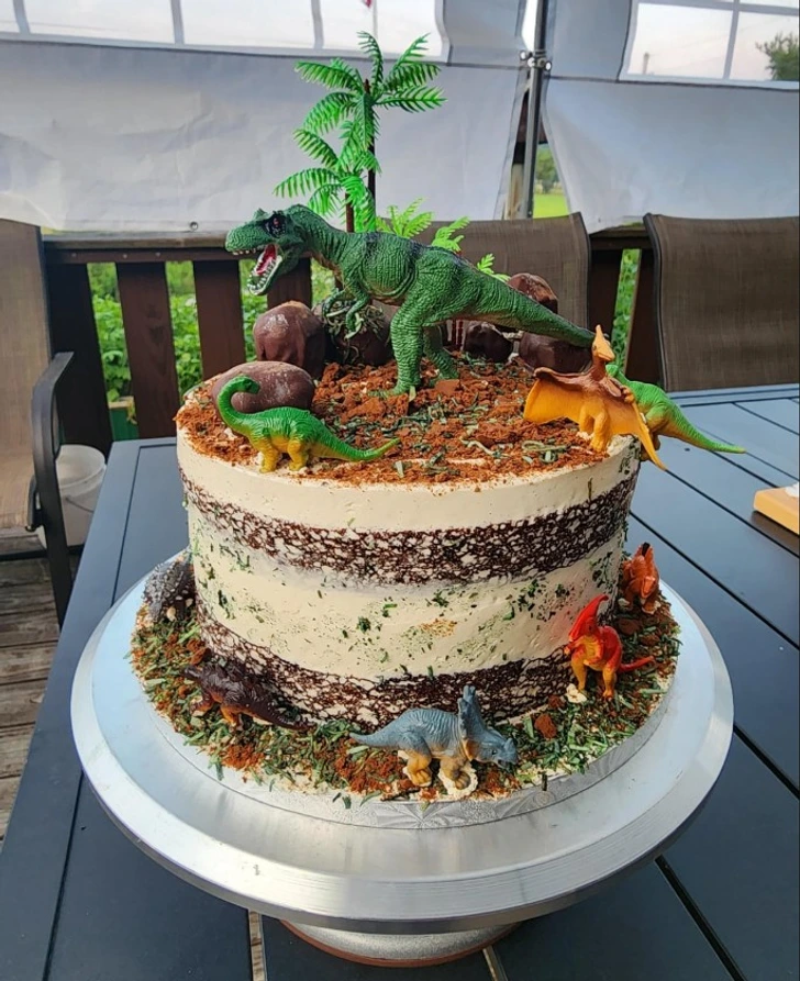 Narozeninová torta s dinosauřími figúrkami a lesnou tématikou na vonkajšej terase.