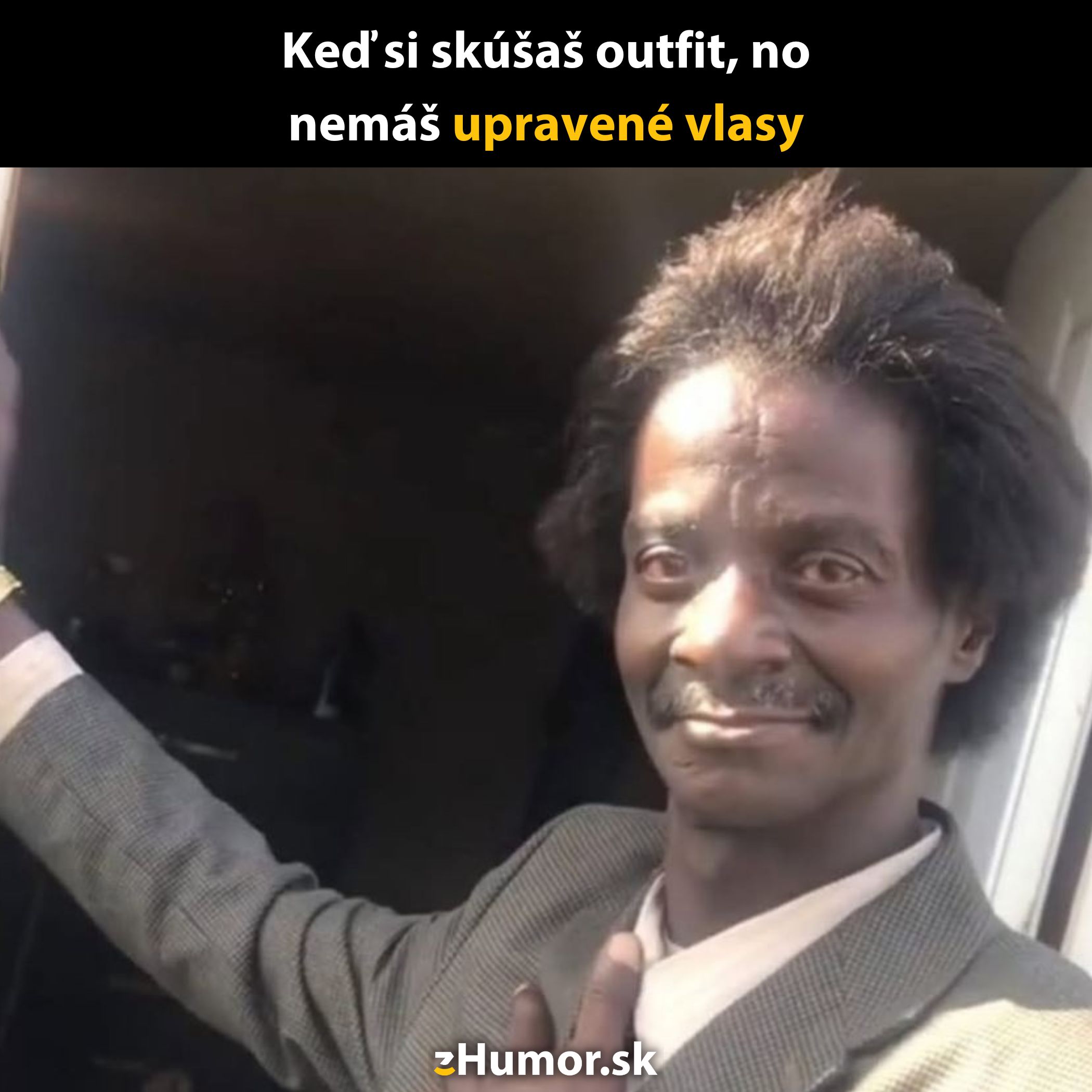 Muž v obleku s upraveným výrazom a neupravenými vlasmi stojí vo dverách.