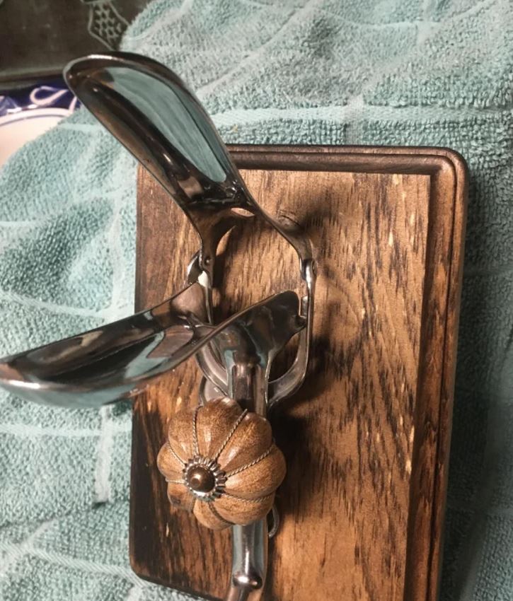 Antik kolízne zrkadlo na drevenom podklade, zdobené kovovou rukoväťou s dreveným ornamentom.