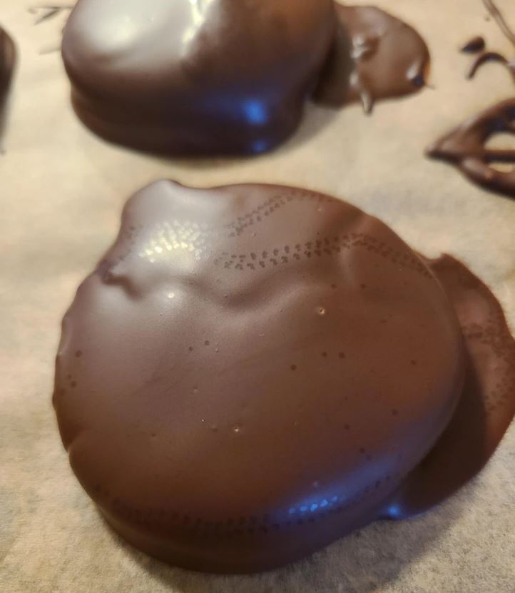 Čokoládová poleva na zákusku s lesklým povrchom, jemná textúra, pripravené na servírovanie.