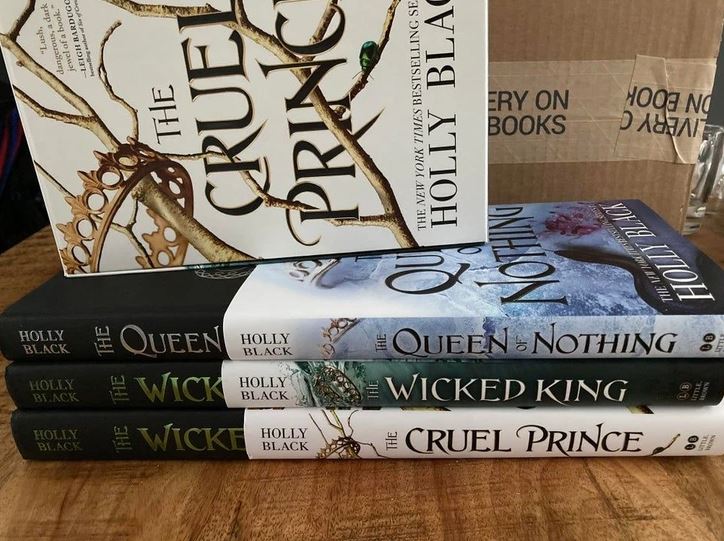 Stoh kníh The Cruel Prince série od Holly Black na drevenom stole.