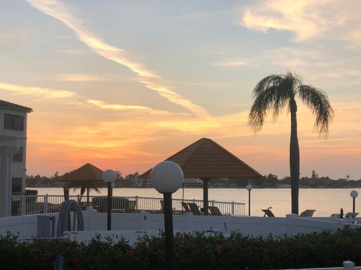 Jazero pri západe slnka s palmou a altánkom, relaxačné prostredie pri vode.