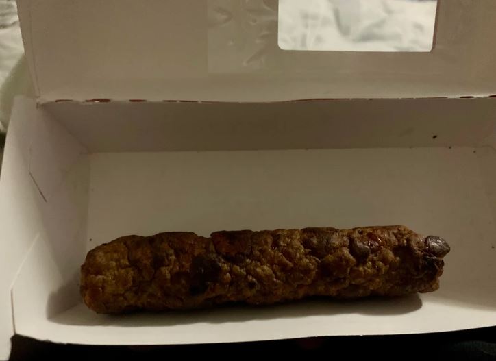 Balená pečená klobása v papierovej krabičke, pripravená na servírovanie.