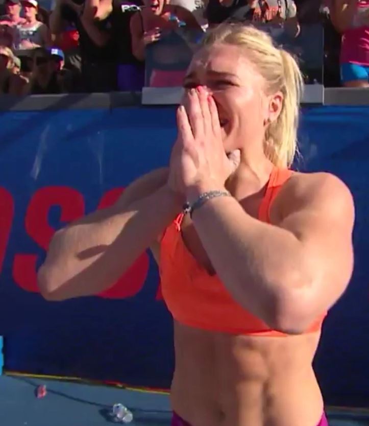 Športovkyňa v oranžovom tope prežíva emotívny moment po dosiahnutí významného úspechu na súťaži.