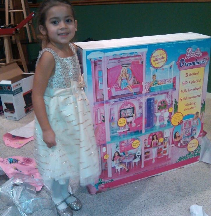 Dievčatko stojí pri krabici s bábikovým domčekom Barbie Dreamhouse, pripravené na hru.