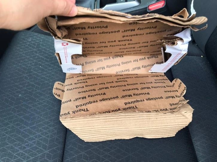 Otvorená kartónová škatuľa položená na sedadle auta, pripravená na balenie a prepravu.