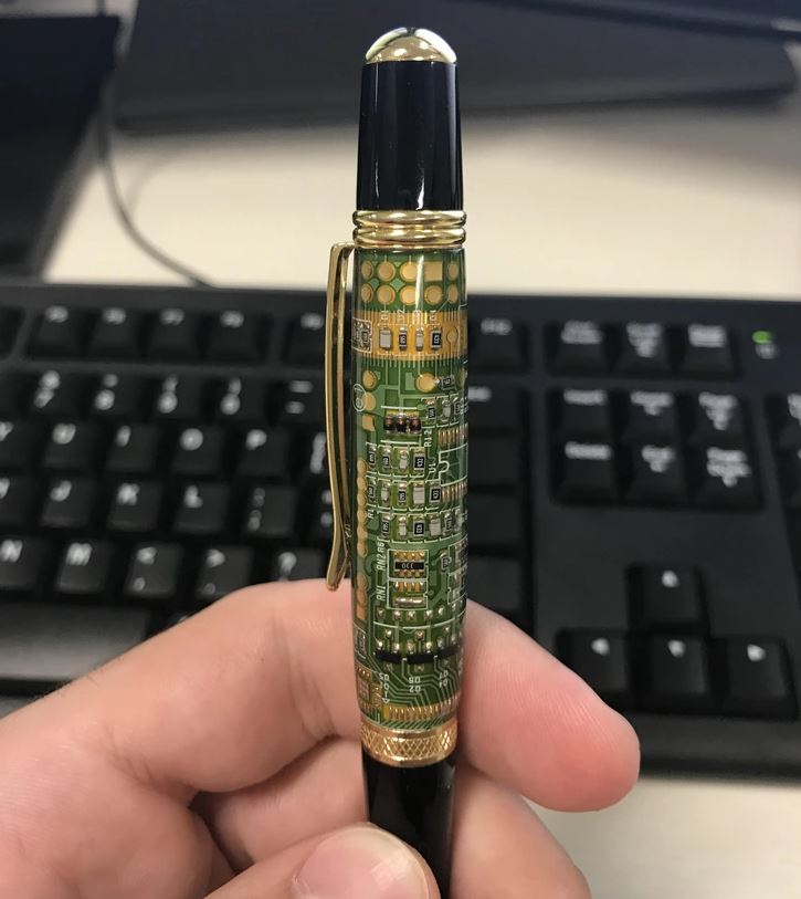 Pero s dizajnom počítačového obvodu držané nad klávesnicou.