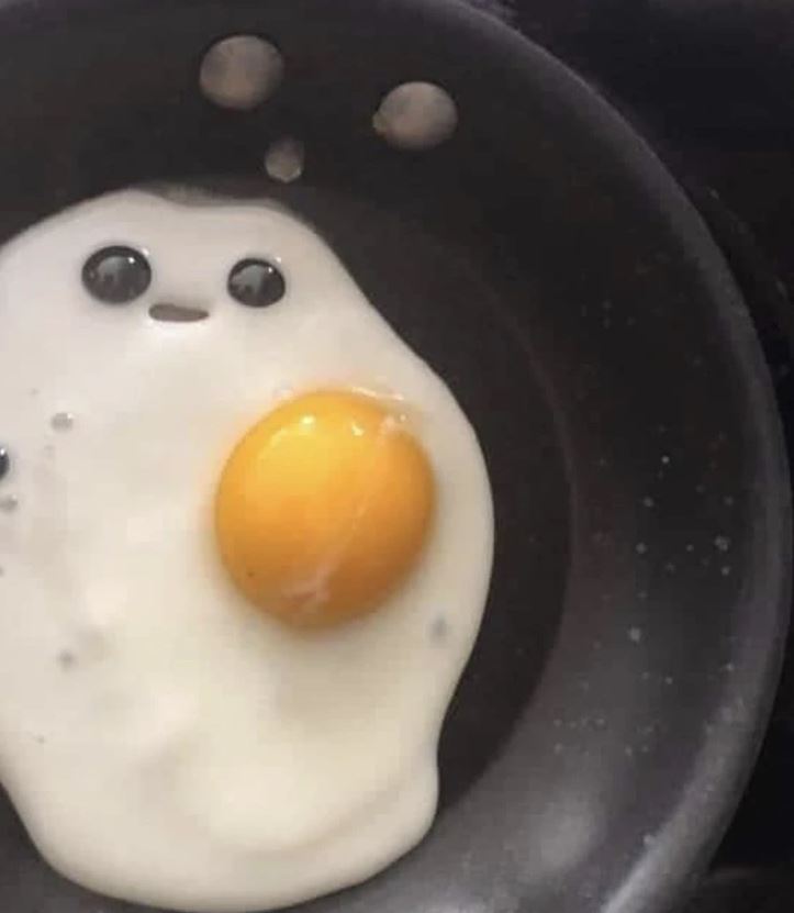 Vyprážané vajíčko na panvici s usmievavou tvárou, vytvorené z bubliniek a žĺtka.