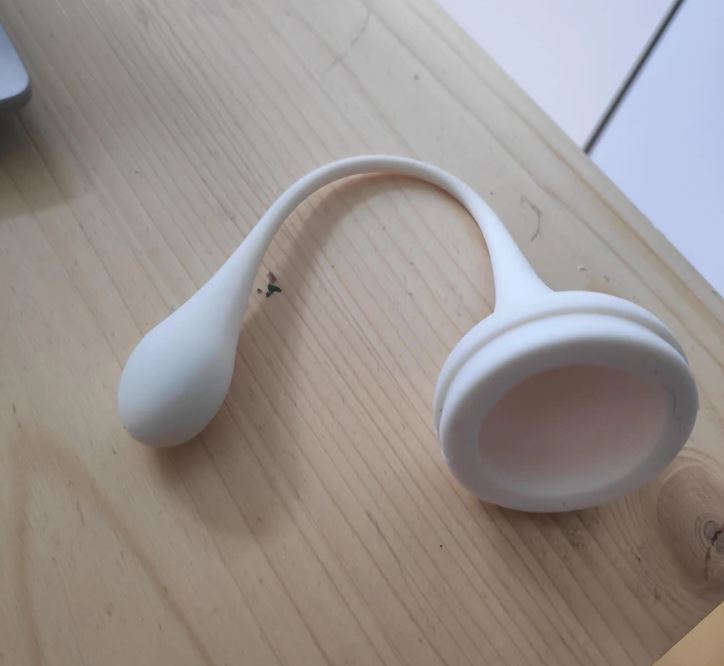 Okrúhla biela silikónová menštruačná pomôcka na drevenom povrchu, zlepšujúca intímnu hygienu žien.