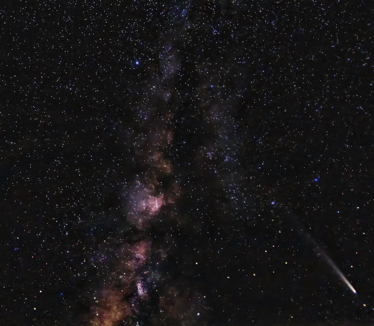 Hviezdna obloha s jasnou Mliečnou cestou a kométou v tmavej nočnej krajine.