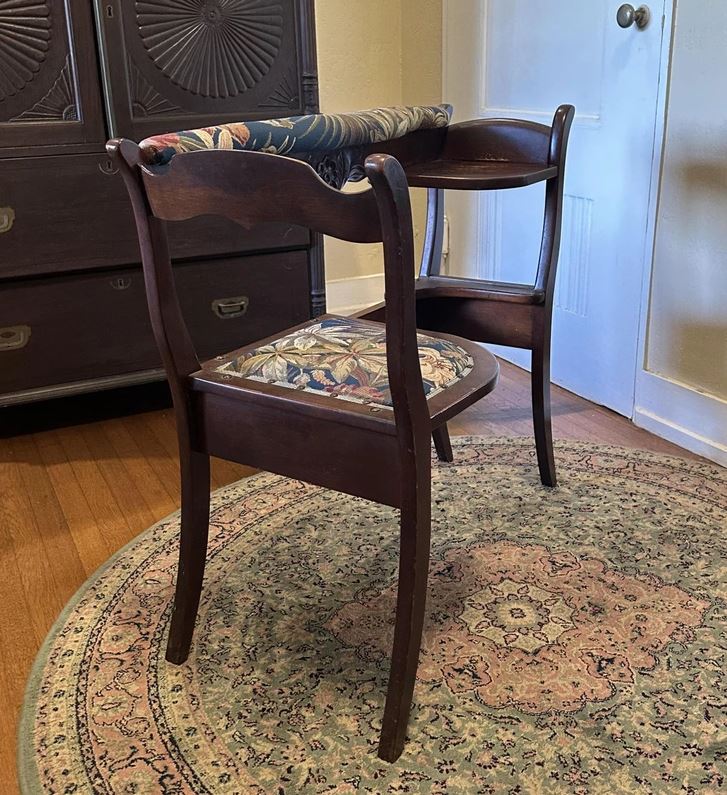 Drevená stolička s kvetinovým čalúnením v rohu miestnosti na zdobenom koberci.