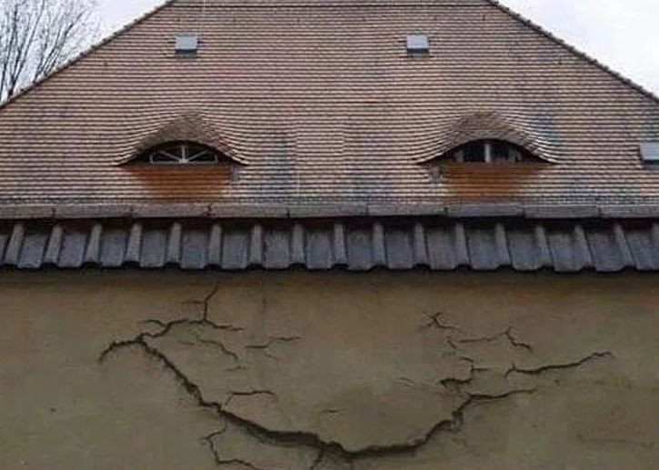 Dom s prasklinami a oknami pripomínajúcimi tvár, vytvára ilúziu úsmevu.