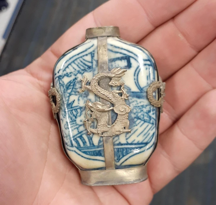 Antická porcelánová fľaša s modrým vzorom draka, držaná v ruke.