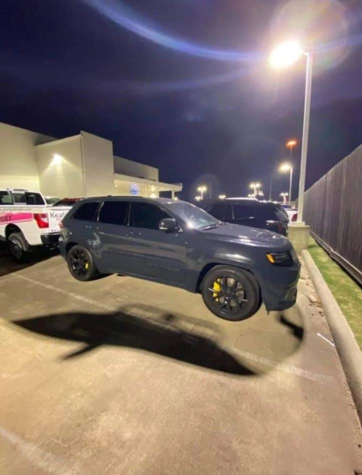 Čierne SUV s tmavými sklami a žltými brzdovými strmeňmi na parkovisku v noci, osvetlené pouličnou lampou.