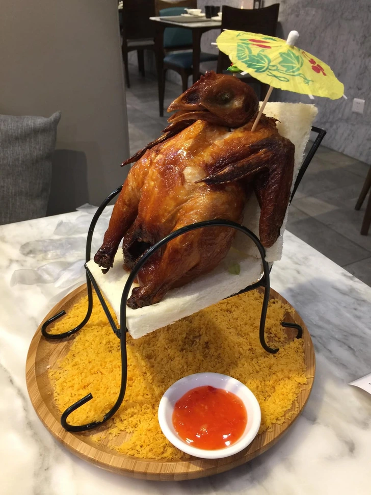 Pečené kura servírované na tanieri v tvare lehátka s omáčkou a dekoračným dáždnikom.