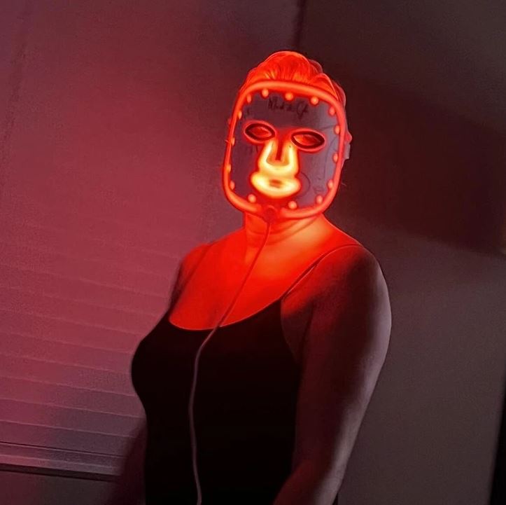 Osoba s LED maskou na tvári svietiacou červeným svetlom.