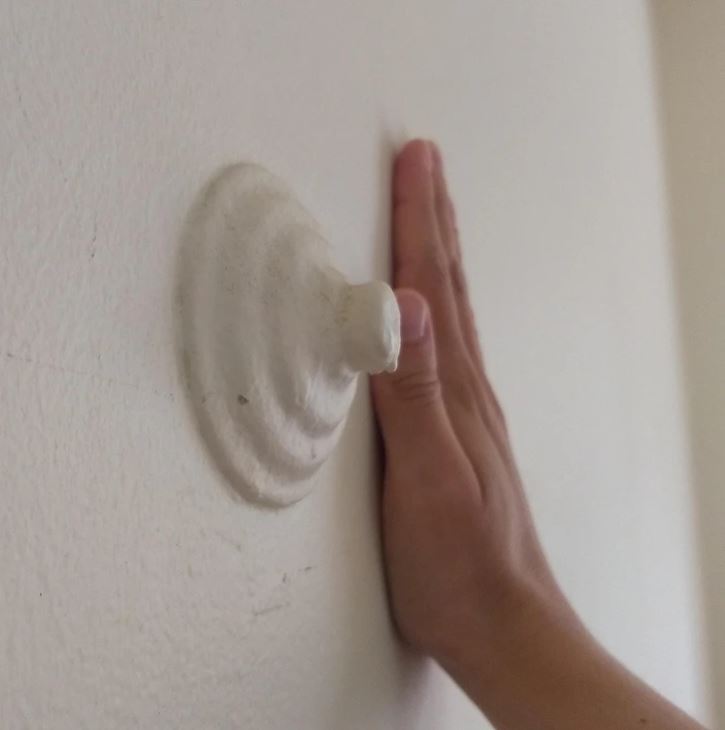 Ruka sa dotýka dorazového nárazníka na stene, zblízka.