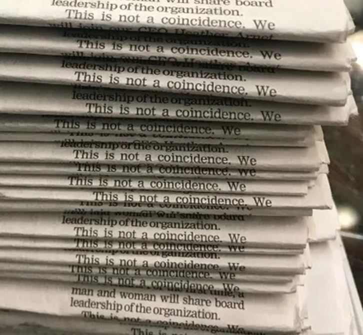 Stoh novín s opakujúcim sa textom This is not a coincidence. We vytvárajú zaujímavý vizuálny efekt.