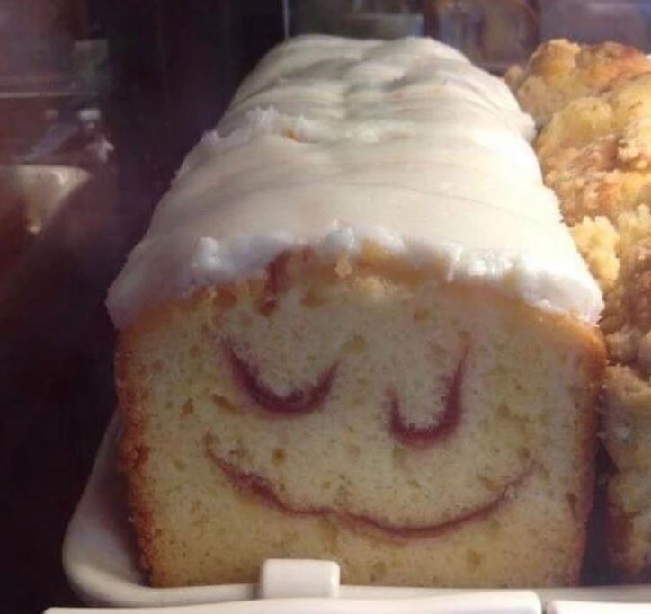 Bábovka s polevou a úsmevom z džemu, vyžarujúca hravosť a sladké potešenie na bielom tanieri.