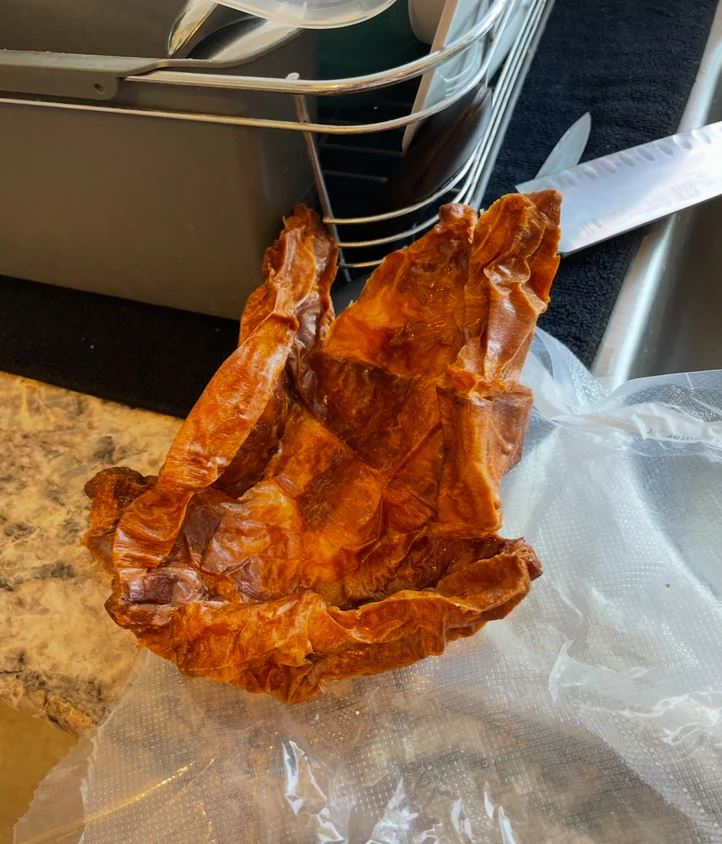 Sušené mäso pripravené na konzumáciu v kuchyni na žulovej doske s vedľa položeným nožom.