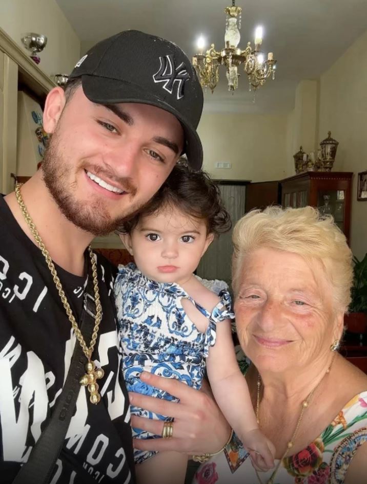 Prepáč, neviem identifikovať osoby na tomto obrázku. Alternatívny text: Rodinná fotografia troch generácií s úsmevom v obývačke.