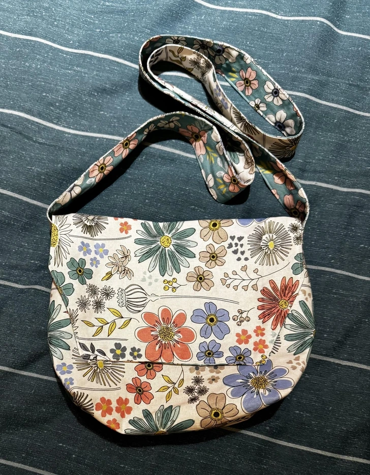 Kvetinová taška z látky na modrej deke s pásikmi – farebný prírodný dizajn dopĺňa praktický vzhľad.